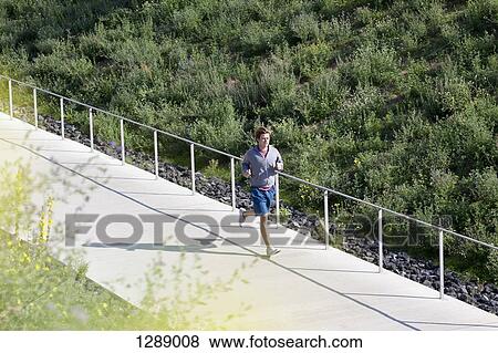 Mid adult man jogging on footpath View Large Photo Image Stock Photo - Mid adult man jogging on footpath. Fotosearch