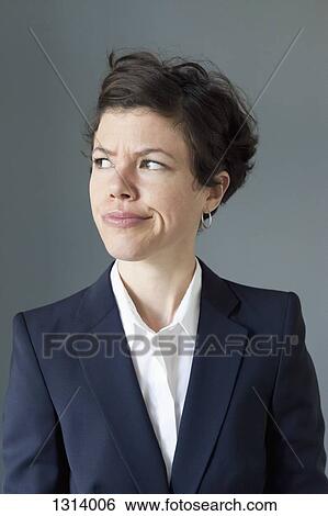Mid adult woman frowning while looking away, close-up View Large Photo Image Stock Photograph - Mid adult woman frowning while looking away, close-up. Fotosearch