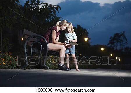 Stock Photo - Mother and daughter using digital tablet in park. Fotosearch