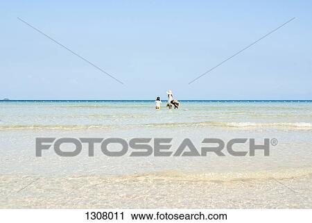 Stock Image - Mother with daughter and son enjoying at beach, distant. Fotosearch