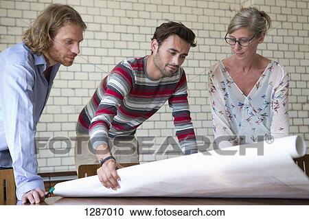 Stock Image - Office colleagues discussing on plan. Fotosearch