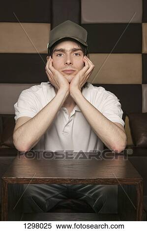 Stock Photography - Portrait of a sad man sitting at a table. Fotosearch