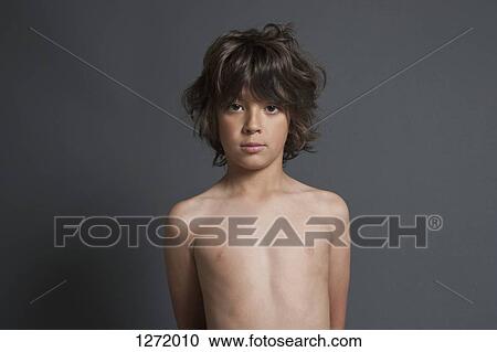 Stock Image - Portrait of shirtless boy standing against gray background. Fotosearch