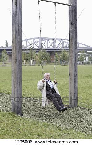 Stock Photograph - Senior man sitting on swing in park. Fotosearch
