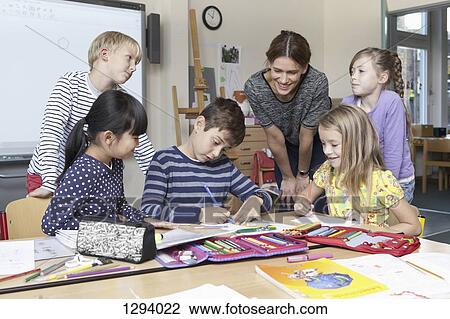Stock Image - Teacher with students in classroom. Fotosearch