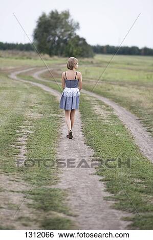 Teenage girl walking on dirt track View Large Photo Image Stock Photograph - Teenage girl walking on dirt track. Fotosearch
