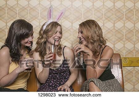 Stock Image - Three women drinking cocktails together. Fotosearch