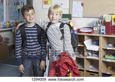 Stock Photo - Two Boys standing side by side in classroom. Fotosearch