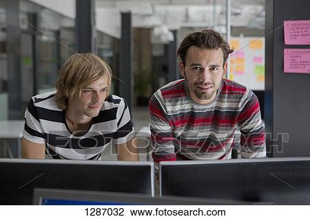 Two men working on computer in office View Large Photo Image Stock Image - Two men working on computer in office. Fotosearch