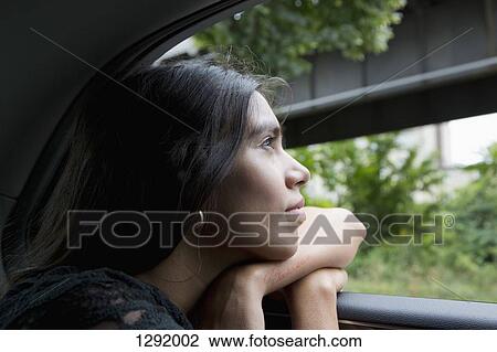 Stock Image - Woman sitting in car and looking through window, close-up. Fotosearch