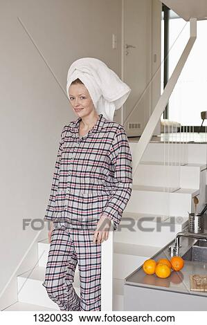 Stock Image - Woman with hair wrapped in towel standing on staircase, portrait. Fotosearch