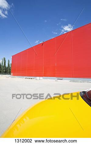 Stock Image - Yellow car beside red wall. Fotosearch