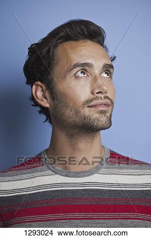 Picture - Young adult man looking up, close-up. Fotosearch
