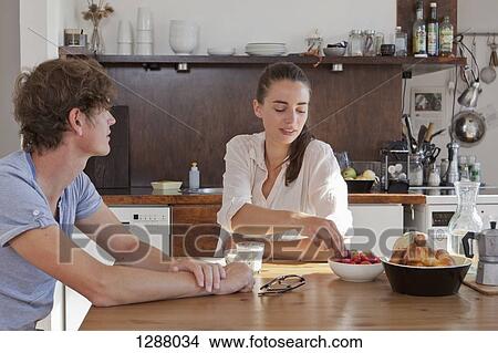 Picture - Young couple having breakfast at dining table. Fotosearch
