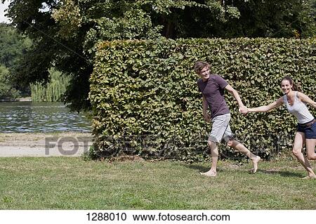 Young couple holding hands and running in park View Large Photo Image Stock Image - Young couple holding hands and running in park. Fotosearch