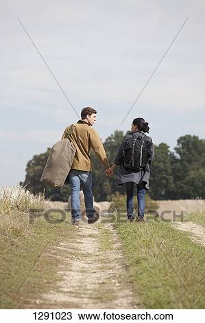 Young couple holding hands and walking through dirt track View Large Photo Image Stock Image - Young couple holding hands and walking through dirt track. Fotosearch