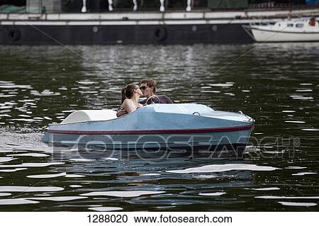 Stock Image - Young couple in paddle boat, kissing. Fotosearch