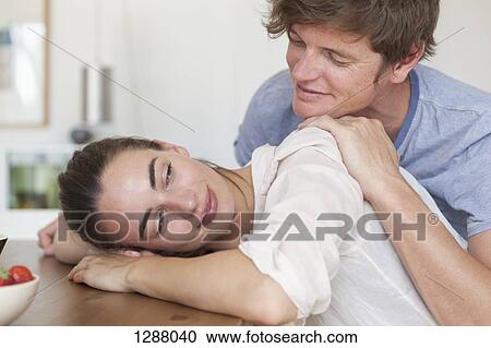 Stock Image - Young couple leaning on table, close-up. Fotosearch