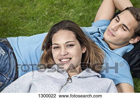 Stock Image - Young couple lying on grass. Fotosearch