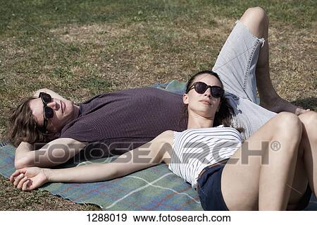 Stock Photo - Young couple lying on picnic blanket. Fotosearch