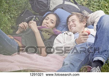 Young couple relaxing in field View Large Photo Image Stock Image - Young couple relaxing in field. Fotosearch
