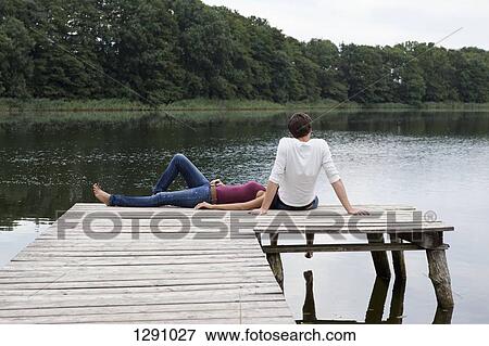 Young couple relaxing on pier View Large Photo Image Stock Photo - Young couple relaxing on pier. Fotosearch