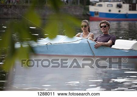 Young couple riding paddle boat on lake View Large Photo Image Stock Image - Young couple riding paddle boat on lake. Fotosearch