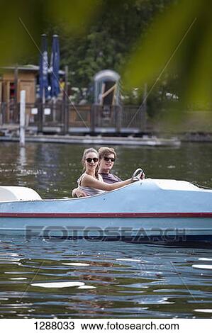 Young couple riding paddle boat on lake View Large Photo Image Stock Image - Young couple riding paddle boat on lake. Fotosearch