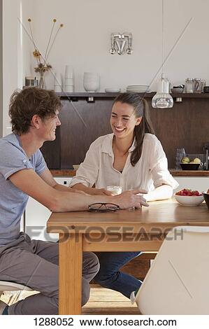 Young couple sitting at dining table in kitchen View Large Photo Image Stock Image - Young couple sitting at dining table in kitchen. Fotosearch