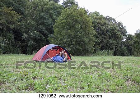 Stock Image - Young couple sitting near dome tent. Fotosearch