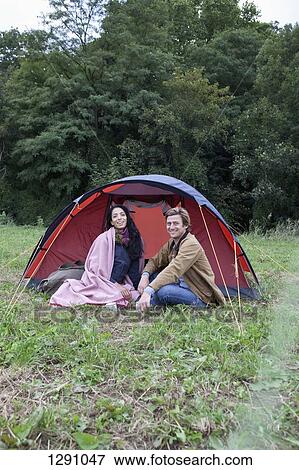 Stock Photo - Young couple sitting near dome tent, smiling. Fotosearch