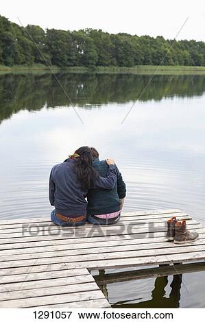 Young couple sitting on pier, rear view View Large Photo Image Stock Photo - Young couple sitting on pier, rear view. Fotosearch