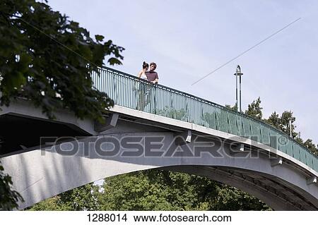 Young couple standing on bridge View Large Photo Image Picture - Young couple standing on bridge. Fotosearch