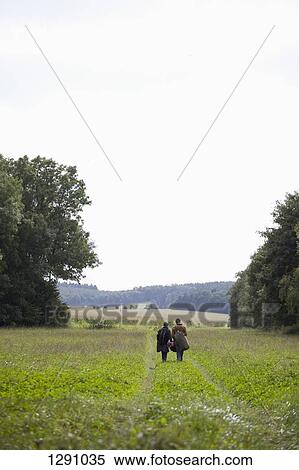Stock Photography - Young couple walking through field. Fotosearch