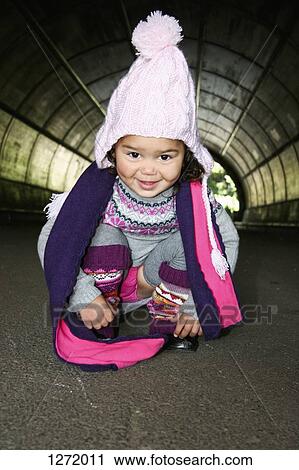 Stock Image - Young girl in winter clothing, looking at camera and smiling. Fotosearch