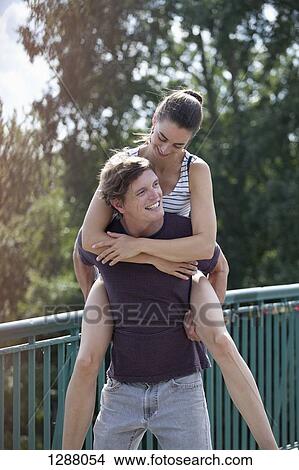 Picture - Young man giving woman piggyback ride. Fotosearch