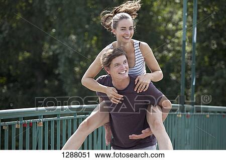 Stock Image - Young man giving woman piggyback ride. Fotosearch