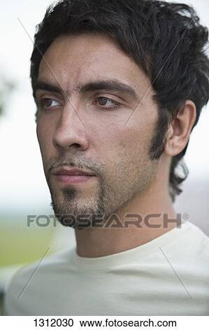 Stock Image - Young man looking away, close-up. Fotosearch