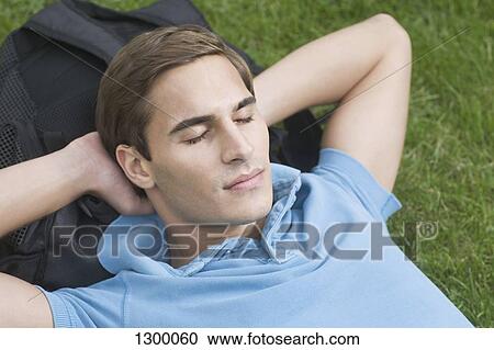 Stock Image - Young man resting on grass. Fotosearch