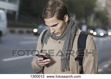 Stock Image - Young man using mobile phone. Fotosearch