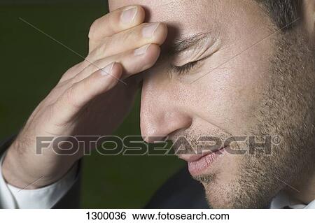 Stock Photograph - Young man with headache, close-up. Fotosearch