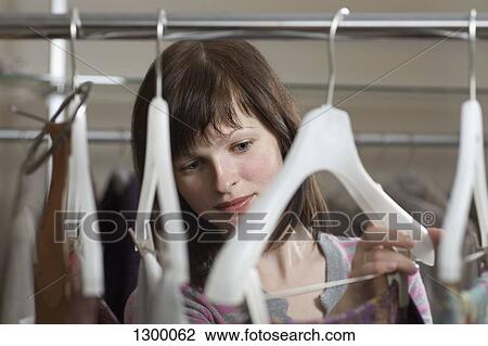 Stock Image - Young woman choosing dress. Fotosearch