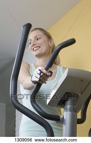 Young woman exercising on exercise bike View Large Photo Image Stock Photograph - Young woman exercising on exercise bike. Fotosearch
