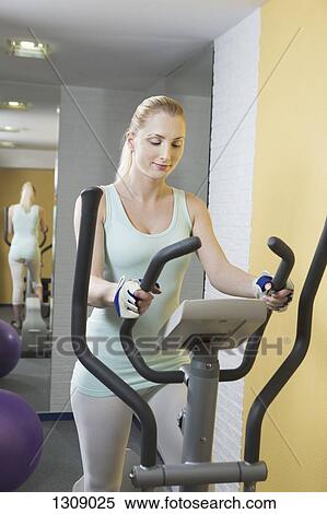 Young woman exercising on exercise bike View Large Photo Image Stock Photography - Young woman exercising on exercise bike. Fotosearch