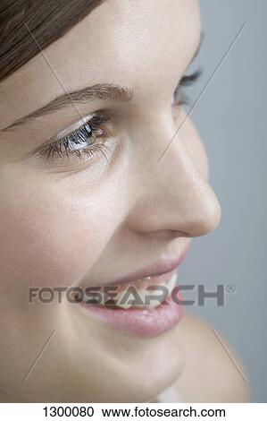 Stock Image - Young woman looking away, close-up. Fotosearch