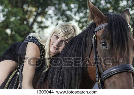 Picture - Young woman lying on horse. Fotosearch