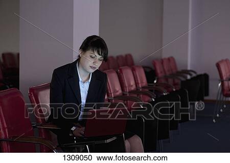Young woman sitting on chair and using laptop View Large Photo Image Stock Image - Young woman sitting on chair and using laptop. Fotosearch