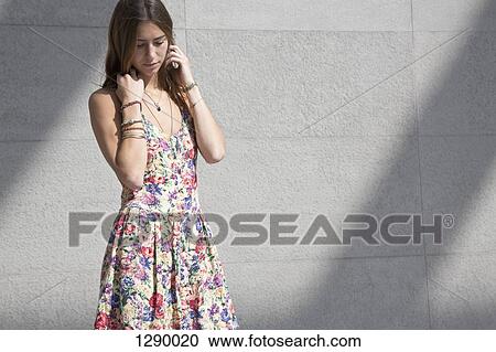 Young woman standing beside wall, looking down View Large Photo Image Stock Image - Young woman standing beside wall, looking down. Fotosearch