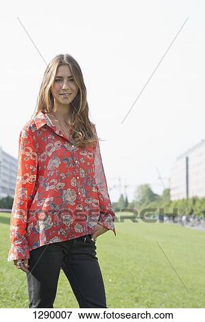 Young woman standing in park, portrait View Large Photo Image Stock Photo - Young woman standing in park, portrait. Fotosearch
