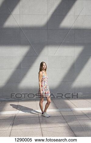 Young woman standing on pavement, looking away View Large Photo Image Stock Photography - Young woman standing on pavement, looking away. Fotosearch